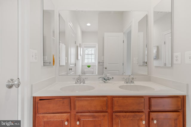 bathroom featuring double vanity, a sink, and toilet