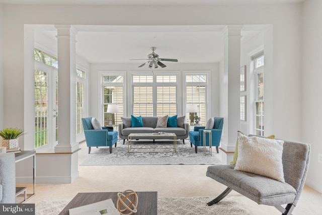 carpeted living room featuring baseboards, ornate columns, and a ceiling fan