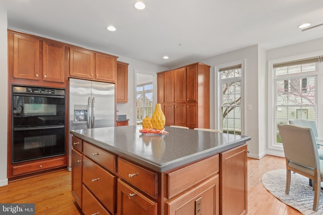 kitchen with dobule oven black, light wood-style flooring, recessed lighting, a kitchen island, and stainless steel refrigerator with ice dispenser