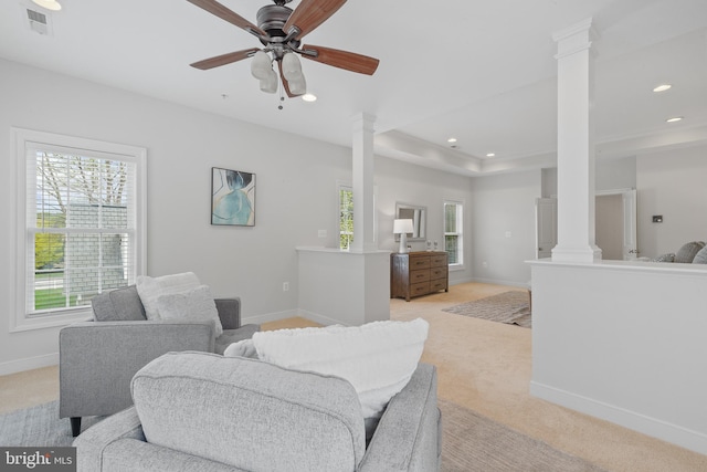 living room featuring baseboards, ornate columns, light colored carpet, and a ceiling fan