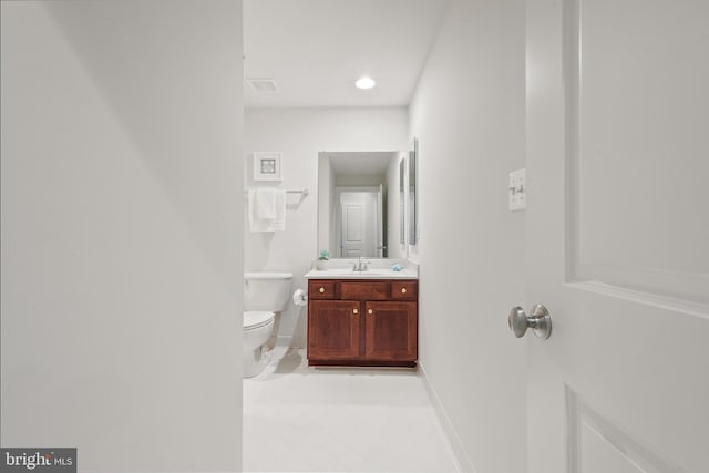 bathroom featuring tile patterned flooring, vanity, baseboards, and toilet