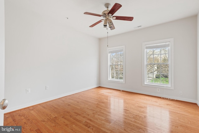 spare room with visible vents, baseboards, a ceiling fan, and wood finished floors