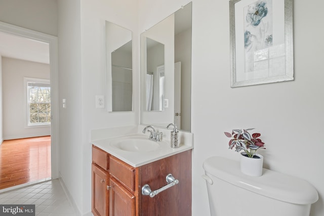 bathroom with tile patterned flooring, toilet, vanity, and baseboards