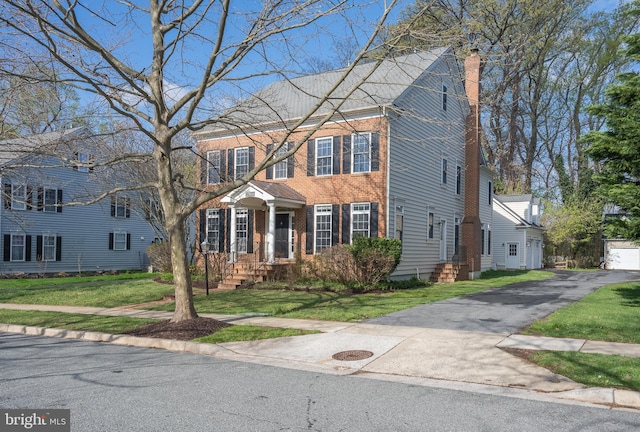 colonial home with a chimney and a front lawn