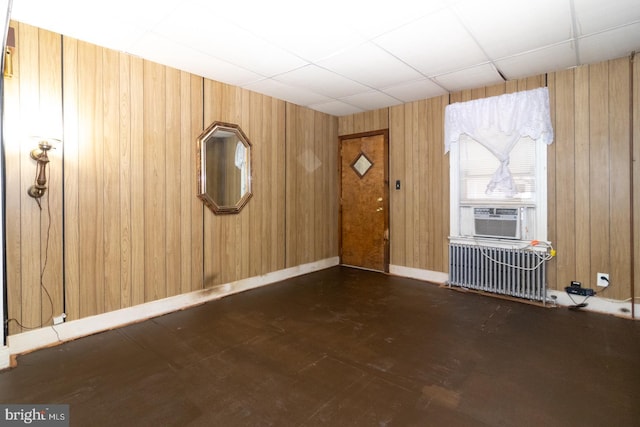 foyer with radiator heating unit, wooden walls, baseboards, and cooling unit