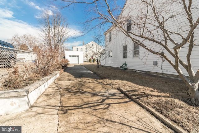 view of property exterior featuring an outbuilding, driveway, a detached garage, and fence