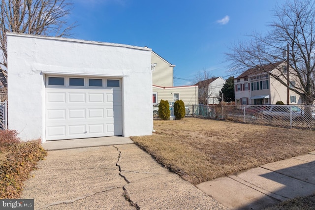 view of side of home with a garage, concrete driveway, fence, and stucco siding