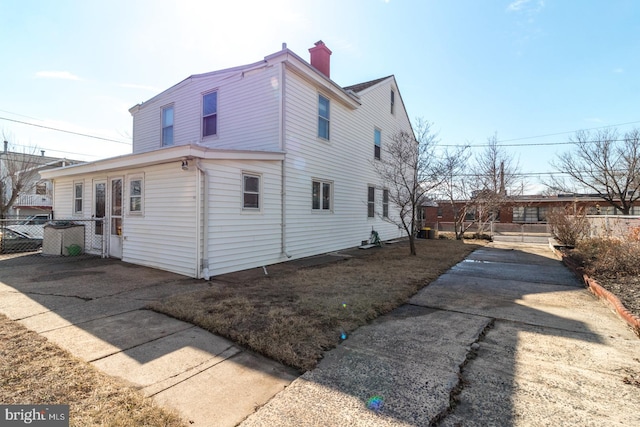 view of property exterior featuring a chimney and fence