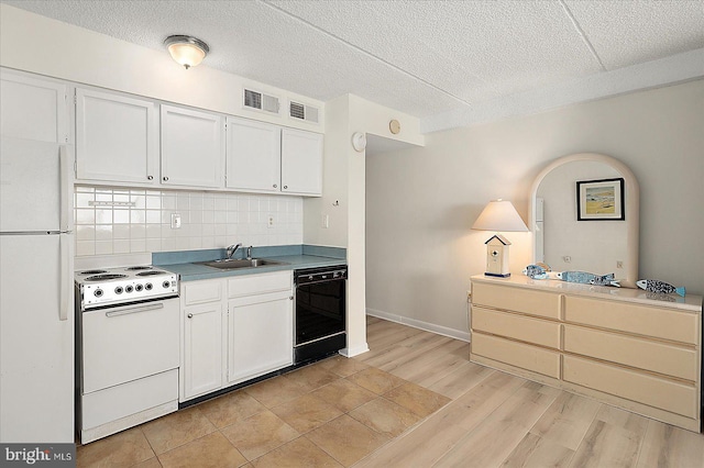 kitchen with white appliances, backsplash, a sink, and white cabinets