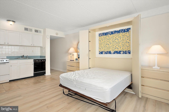 bedroom featuring light wood-style flooring, visible vents, and a sink