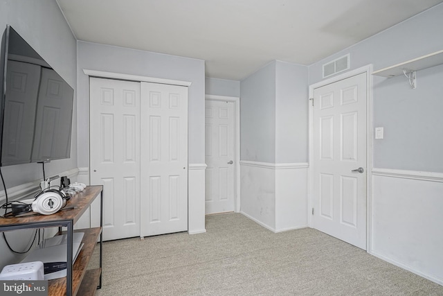 bedroom with a closet, visible vents, and light colored carpet