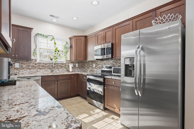 kitchen featuring a sink, stainless steel appliances, light stone countertops, and visible vents