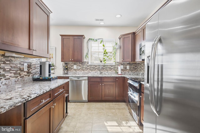 kitchen featuring visible vents, a sink, light stone counters, appliances with stainless steel finishes, and light tile patterned floors