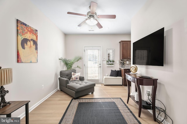 living area featuring light wood-style flooring, baseboards, and ceiling fan