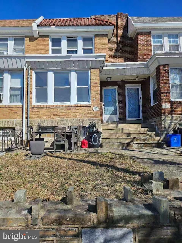 view of front of home with a tile roof, fence, and brick siding