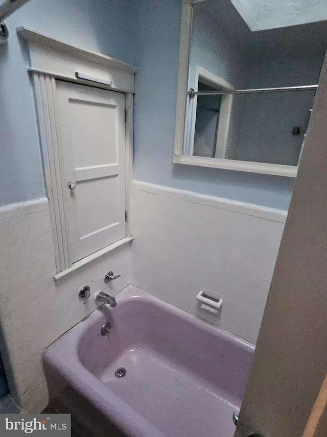 full bath with a wainscoted wall and tile walls