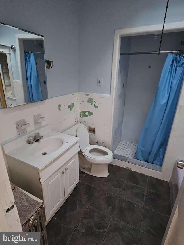 bathroom featuring a wainscoted wall, tile walls, toilet, a shower stall, and vanity