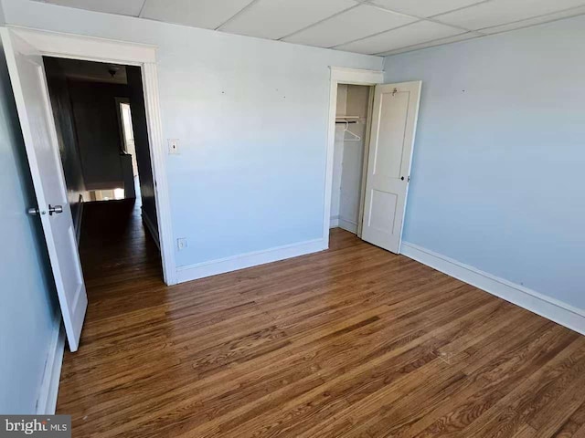 spare room with a drop ceiling, baseboards, and wood finished floors