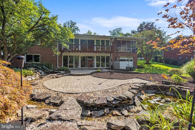 back of property with brick siding, a lawn, an attached garage, a sunroom, and a patio area