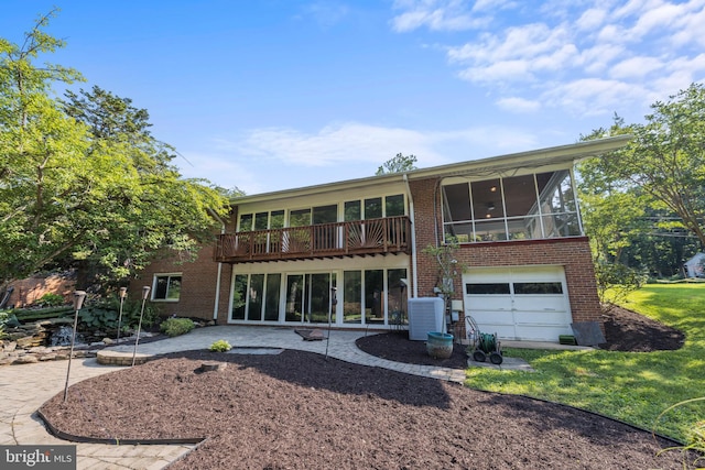 back of house featuring a garage, a patio, a sunroom, cooling unit, and brick siding