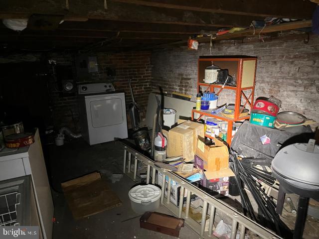 unfinished basement with washer / dryer and brick wall