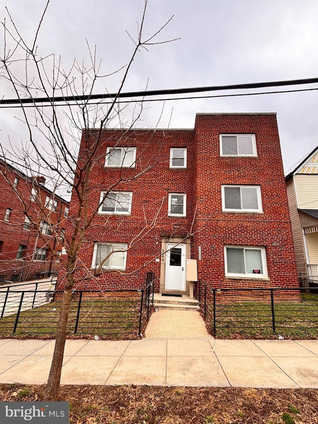 townhome / multi-family property with brick siding and a fenced front yard