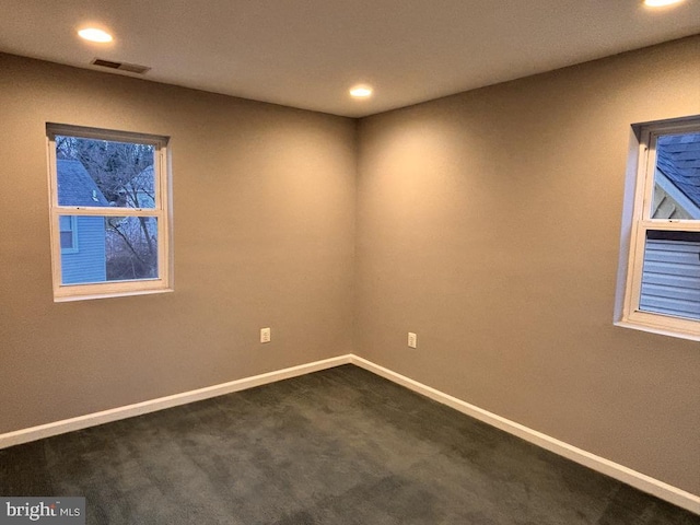 spare room featuring dark colored carpet, recessed lighting, visible vents, and baseboards