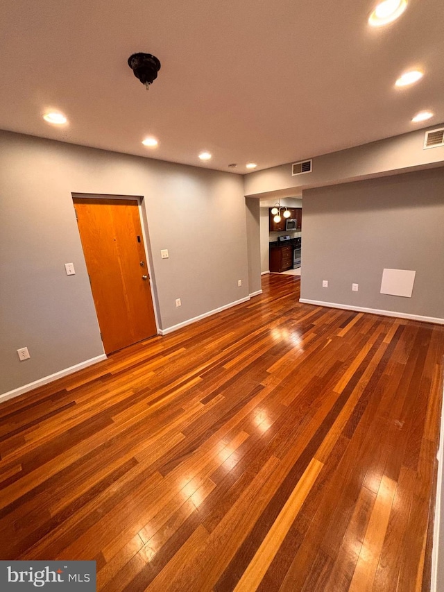 unfurnished living room featuring baseboards, hardwood / wood-style flooring, visible vents, and recessed lighting