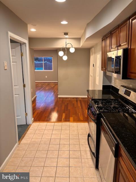 kitchen featuring light tile patterned flooring, stainless steel microwave, baseboards, and gas range