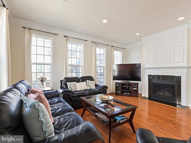 living room featuring recessed lighting, a fireplace, crown molding, and wood finished floors