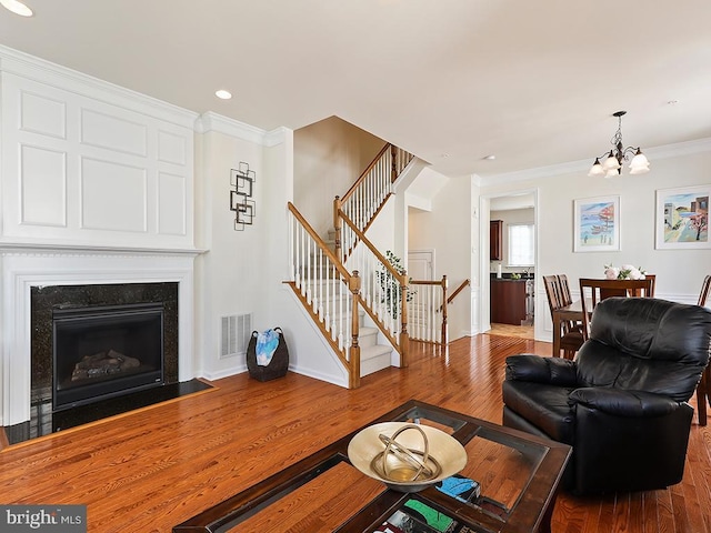 living room with visible vents, a premium fireplace, ornamental molding, wood finished floors, and stairs