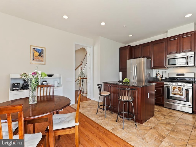 kitchen with recessed lighting, a kitchen island, stainless steel appliances, and a kitchen breakfast bar