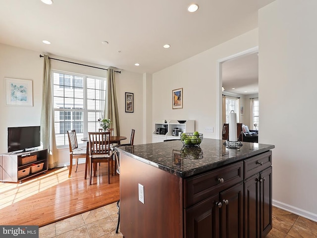 kitchen featuring recessed lighting, dark stone counters, dark brown cabinetry, and light tile patterned floors