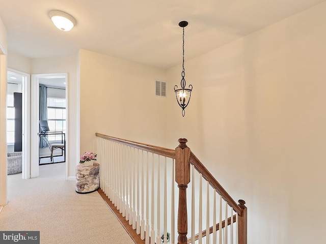 hall featuring a chandelier, carpet floors, an upstairs landing, and visible vents