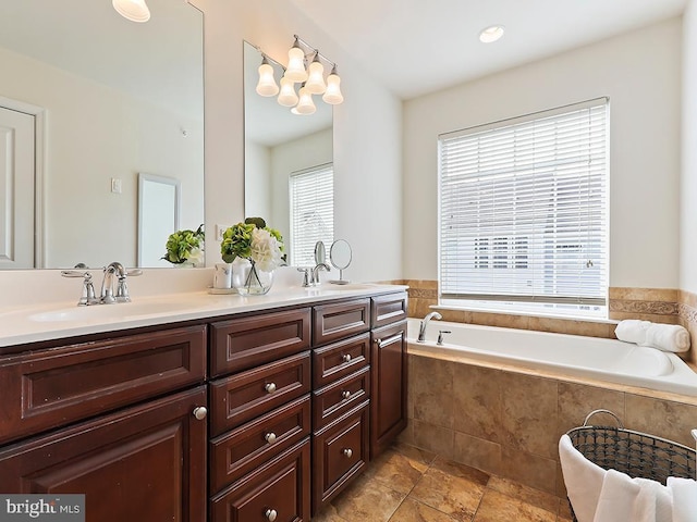 bathroom featuring double vanity, a garden tub, and a sink