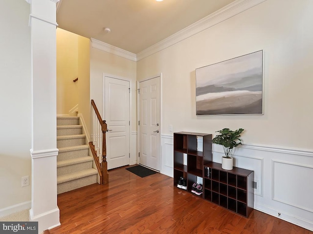 entryway with wood finished floors, stairs, ornamental molding, wainscoting, and ornate columns