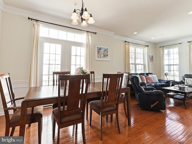 dining area featuring ornamental molding, hardwood / wood-style flooring, and an inviting chandelier