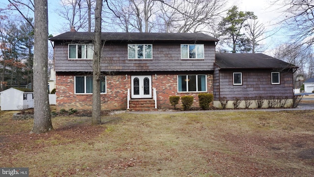 back of property with a chimney, a lawn, french doors, and brick siding