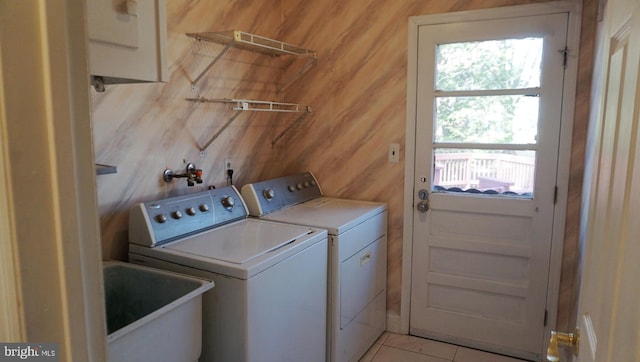 laundry area with laundry area, washing machine and dryer, light tile patterned floors, and a sink