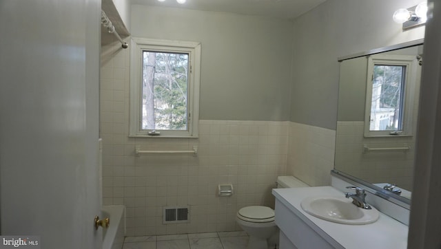 full bath with visible vents, plenty of natural light, tile walls, and toilet