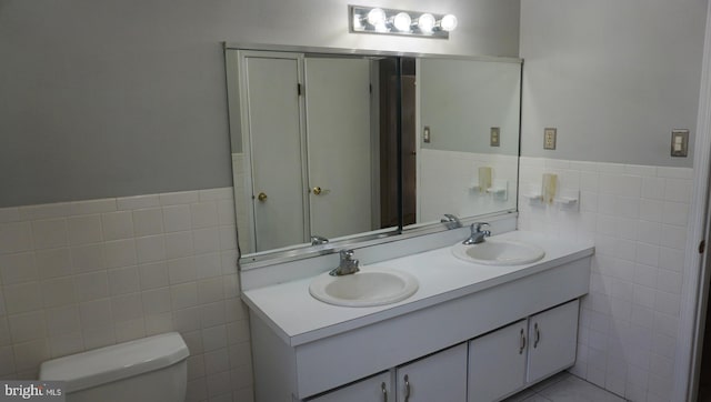 full bath with a sink, tile walls, and toilet