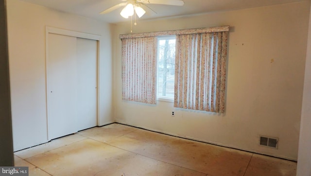 unfurnished bedroom featuring ceiling fan, multiple windows, visible vents, and a closet