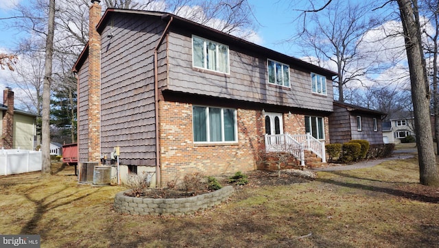 view of front of house featuring a front yard, brick siding, fence, and a chimney