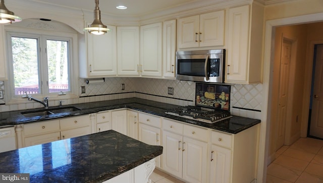 kitchen featuring light tile patterned floors, decorative backsplash, stainless steel microwave, gas cooktop, and a sink