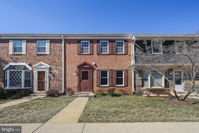 view of property featuring a front lawn and brick siding