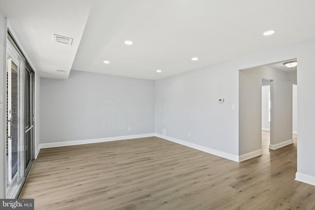 empty room featuring recessed lighting, wood finished floors, visible vents, and baseboards