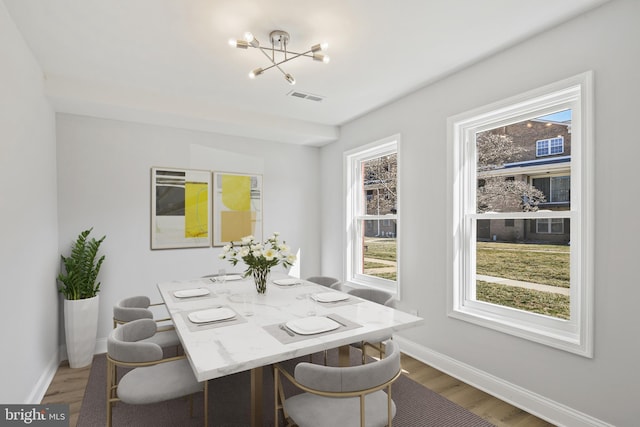 dining space featuring light wood-type flooring, an inviting chandelier, baseboards, and visible vents