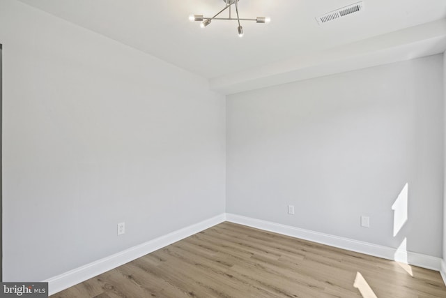 spare room with baseboards, visible vents, and wood finished floors