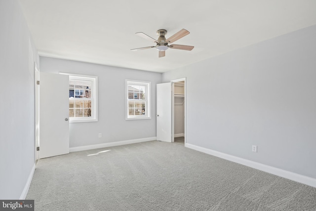 unfurnished bedroom featuring carpet flooring, a spacious closet, and baseboards