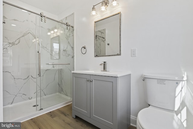 full bathroom featuring toilet, vanity, a marble finish shower, and wood finished floors